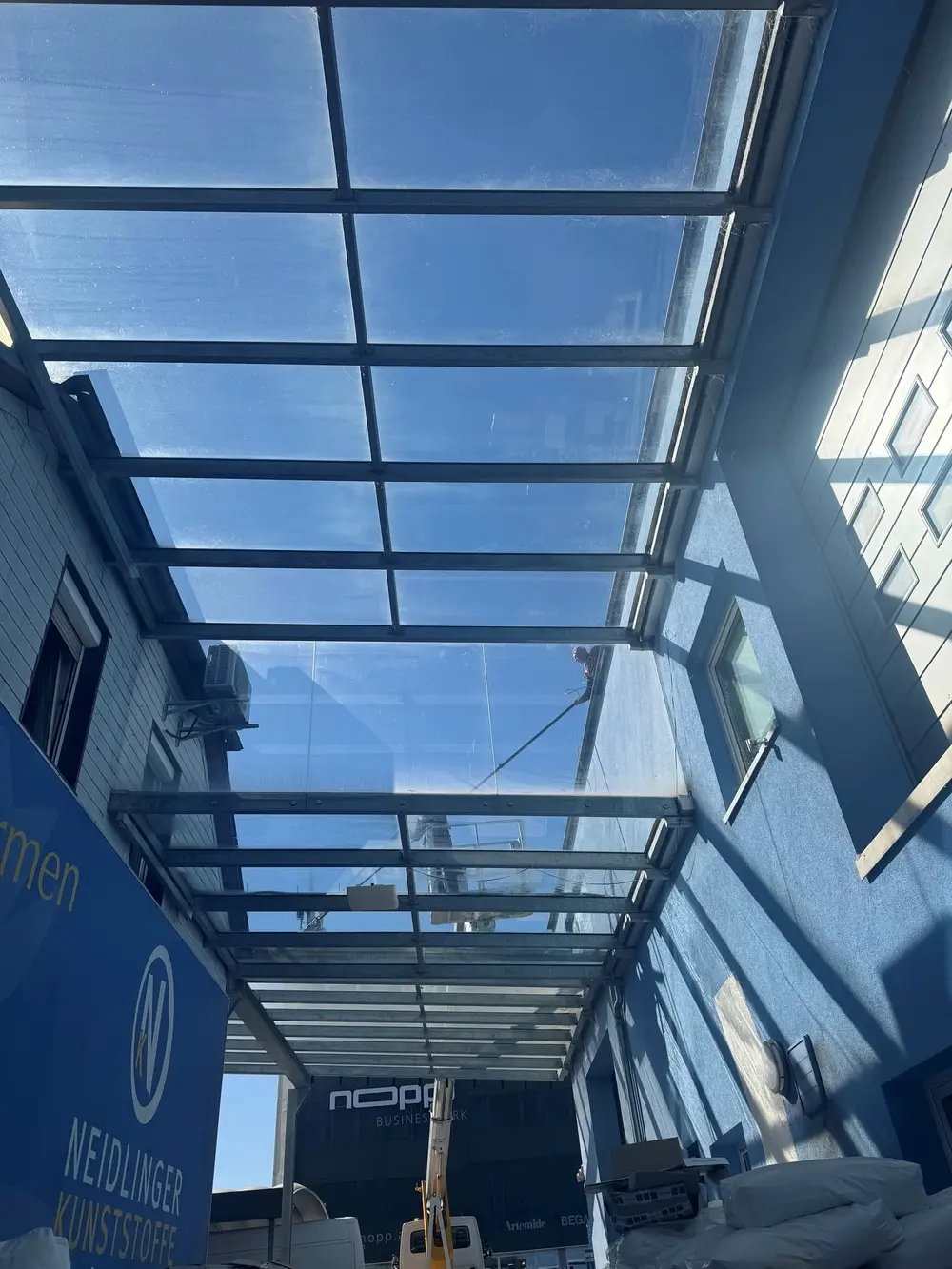 Blick von unten auf die Glasüberdachung während der Reinigung bei Neidlinger Kunststoffe.